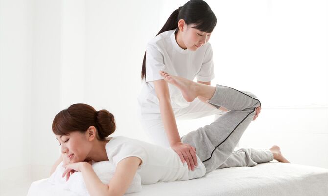 女性の左足を施術するスタッフ
